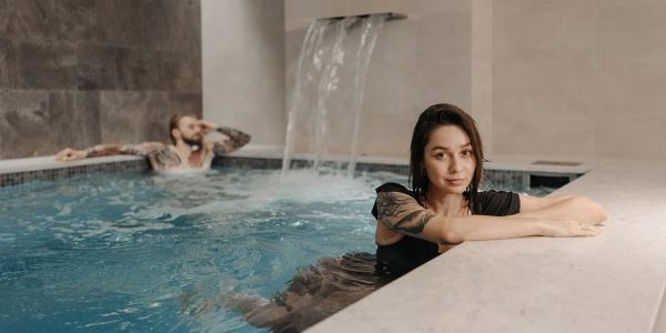 A couple enjoying a relaxing moment together in an indoor pool with a waterfall.