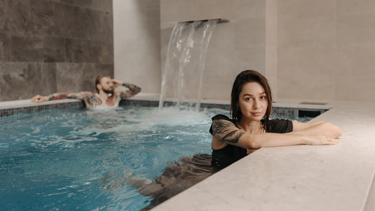 A couple enjoying a relaxing moment together in an indoor pool with a waterfall.